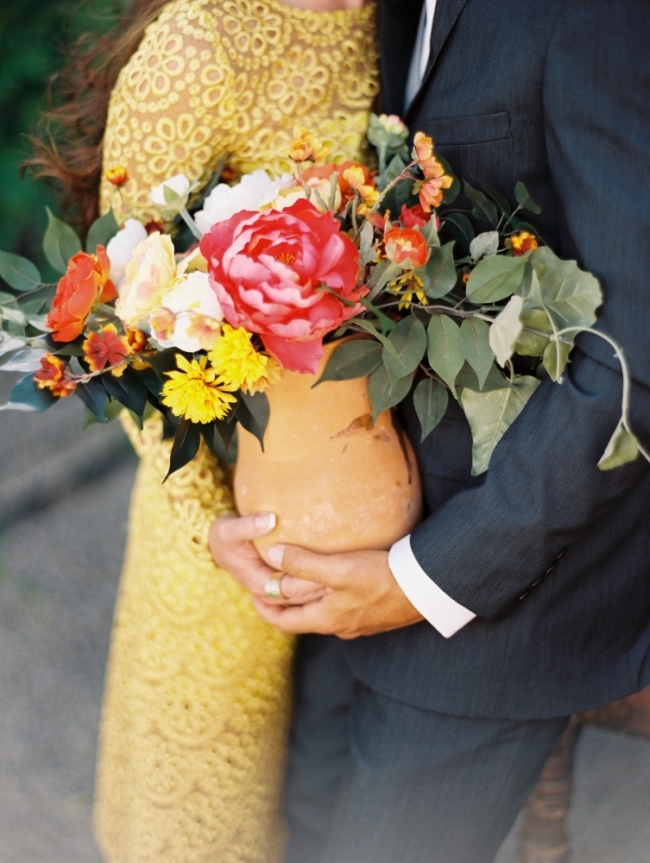 man and woman holding ceramic vase of flowers