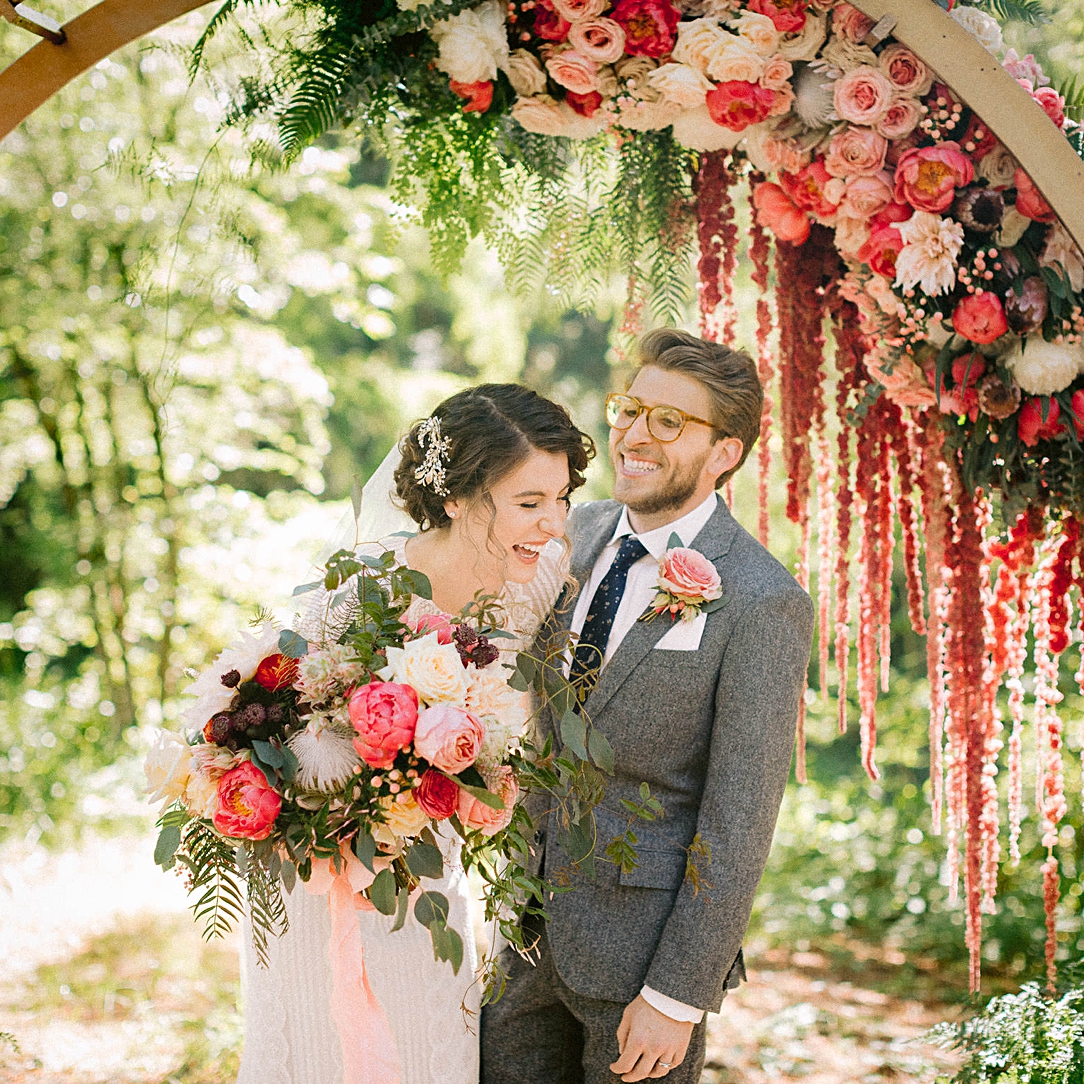 couple wedding altar floral arch laughing