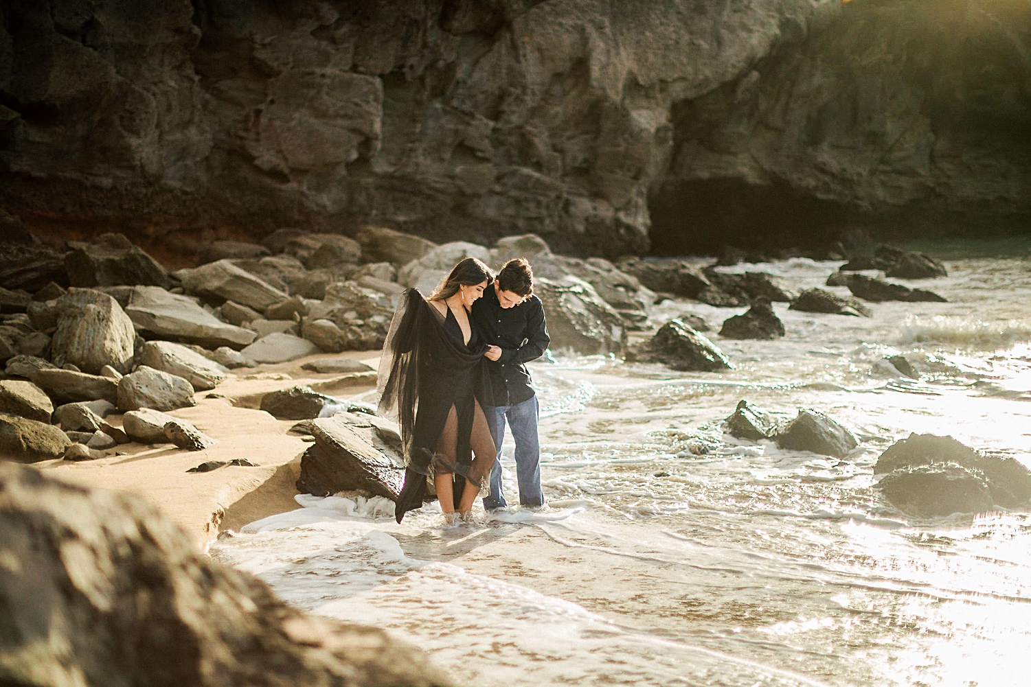 man and woman wearing black wading in surf beach Maui Hawaii elopement sunset