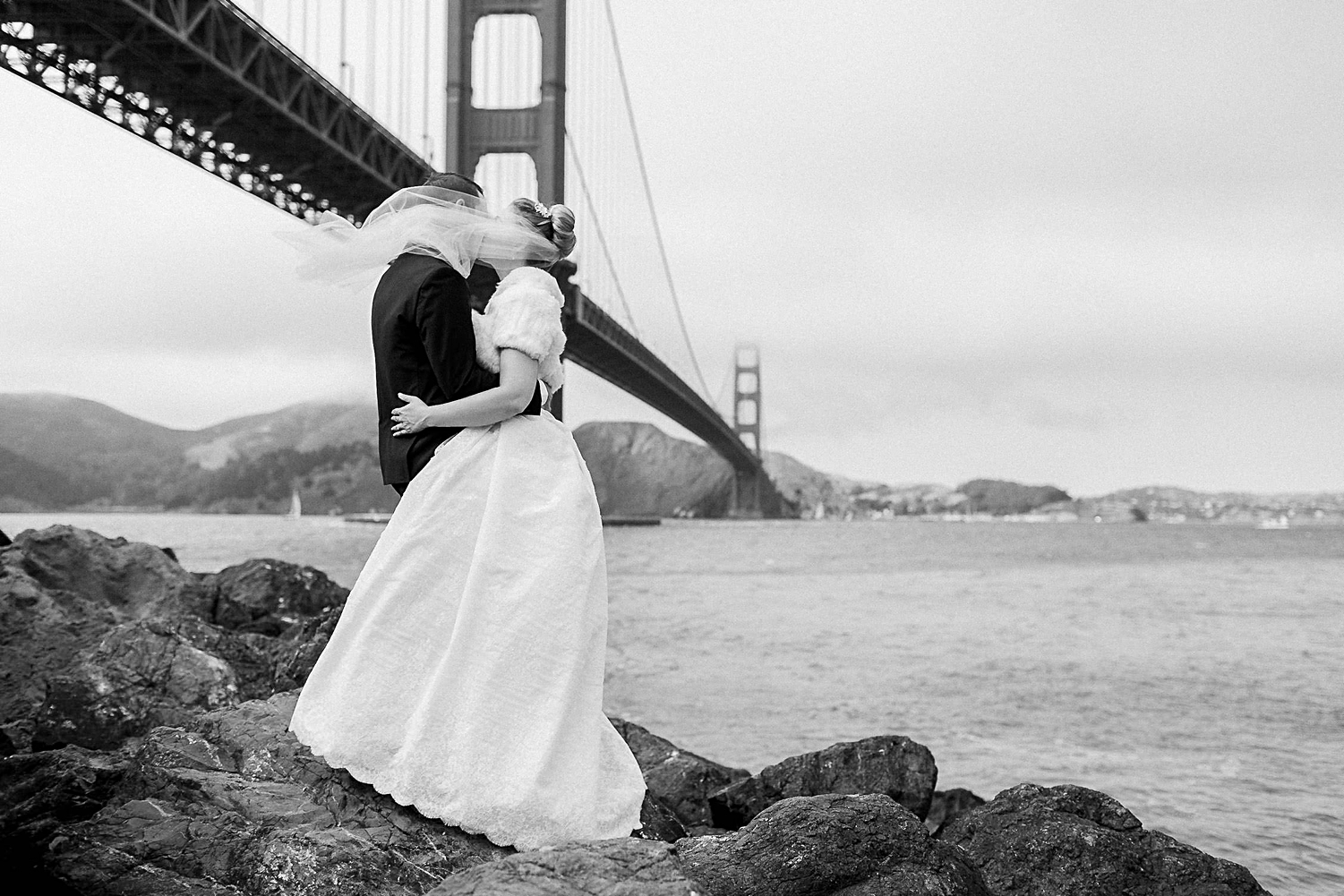 Bride and groom kissing in front of Golden Gate Bridge San Francisco black and white planning destination wedding