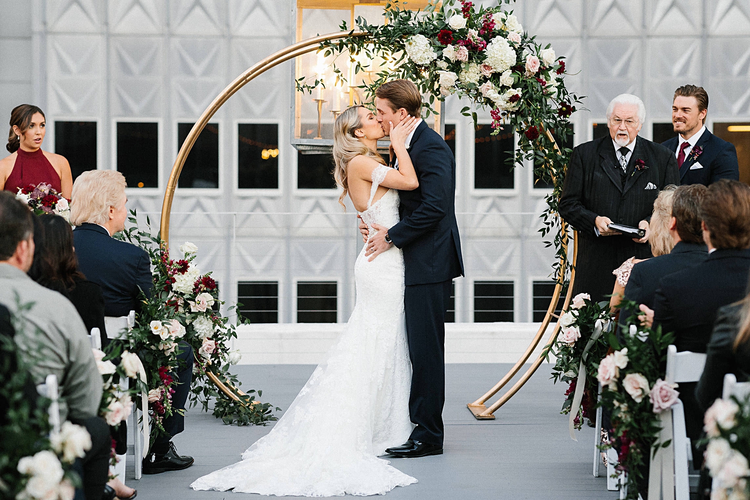 bride and groom first kiss at rooftop wedding ceremony floral arch altar 400 North Ervay Dallas Venue 