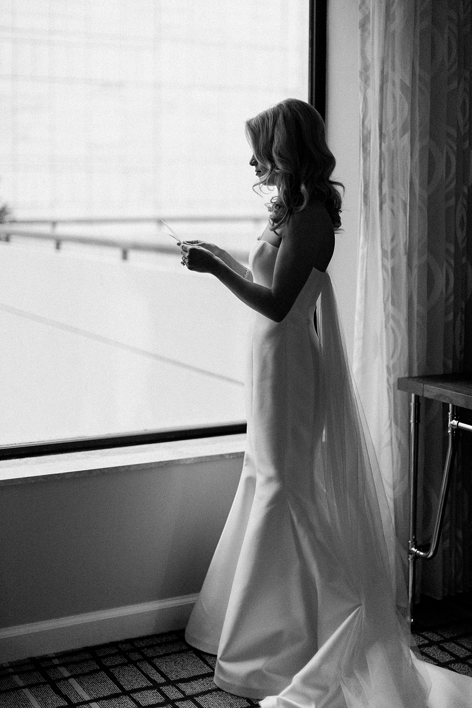bride reading note by a window wedding dress