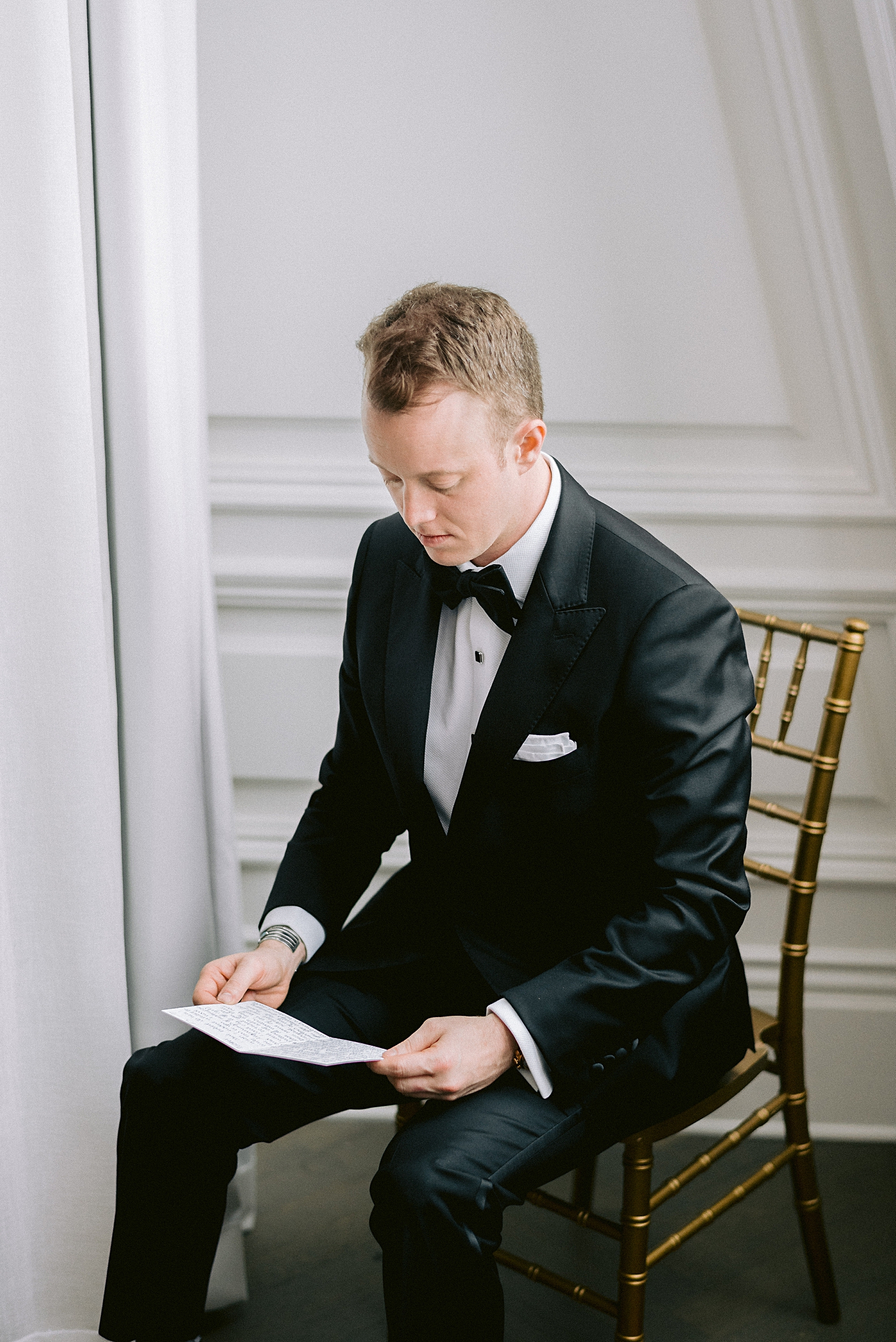 groom in tuxedo reading letter