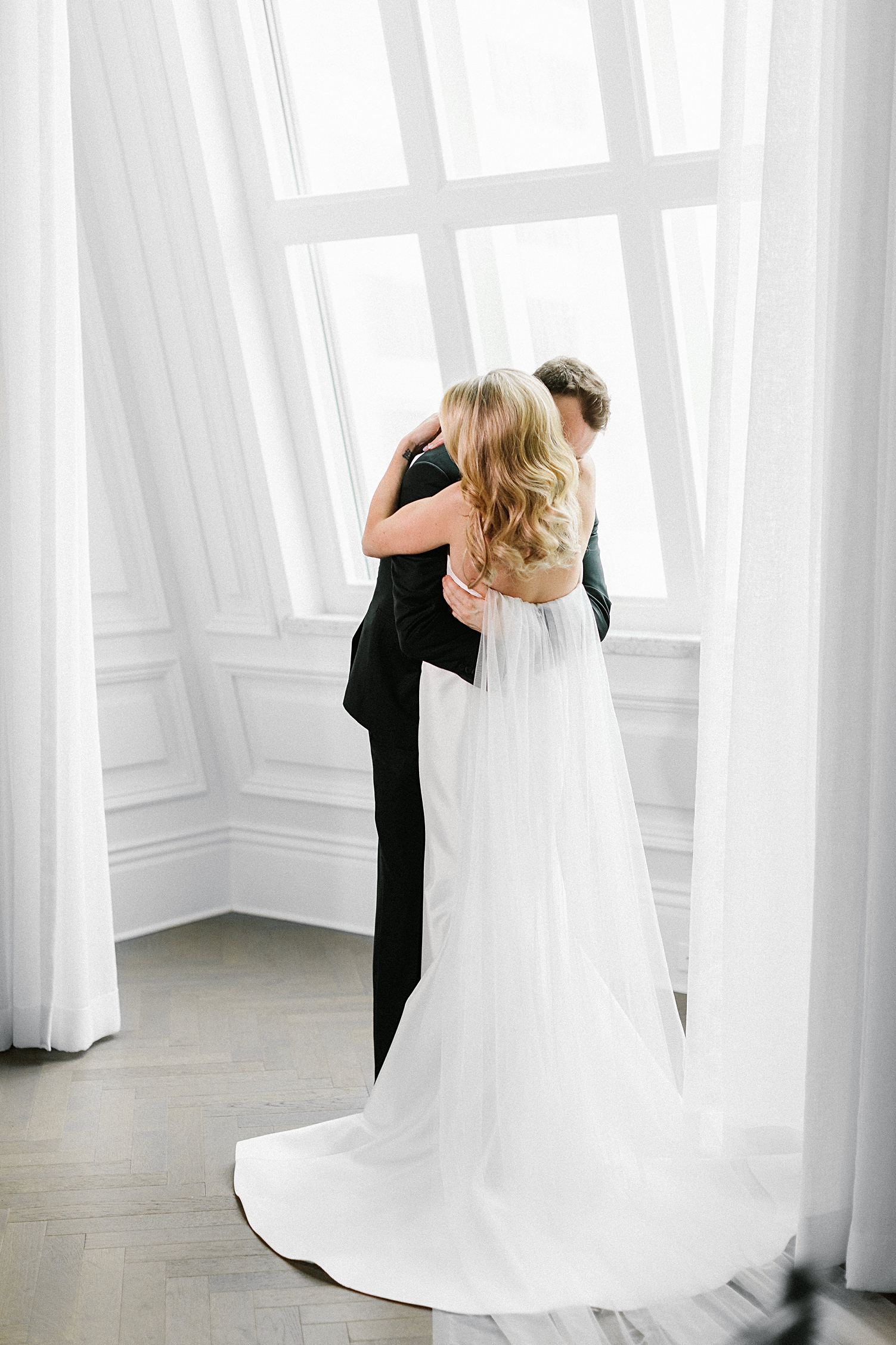 bride and groom hugging in front of window
