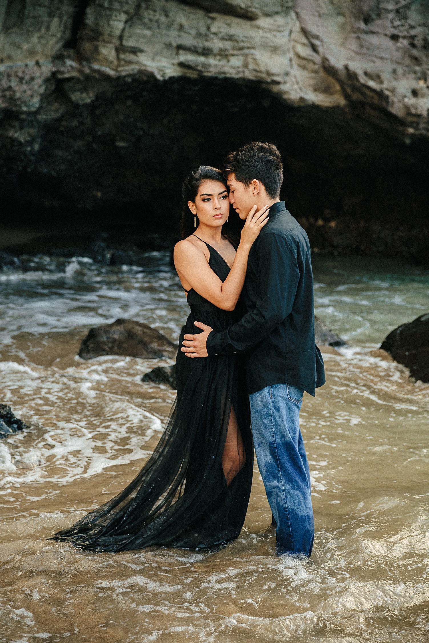 Couple dressed in black engagement on rocky beach