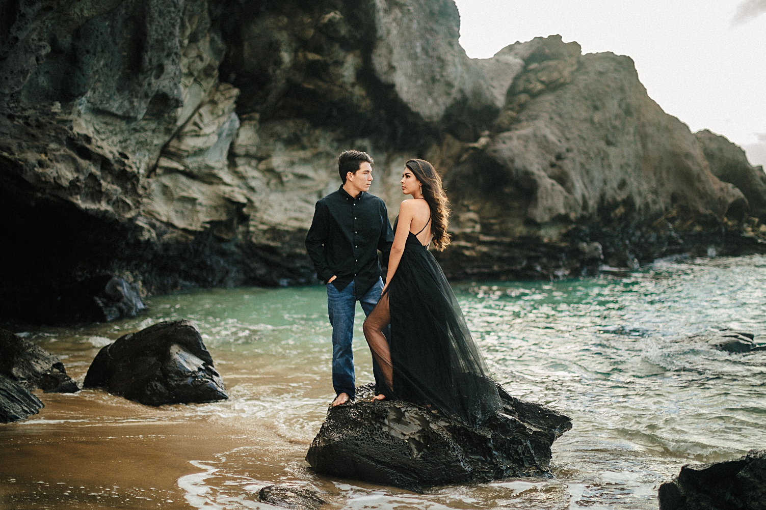 Hawaii couple dressed in black engagement on rocky beach