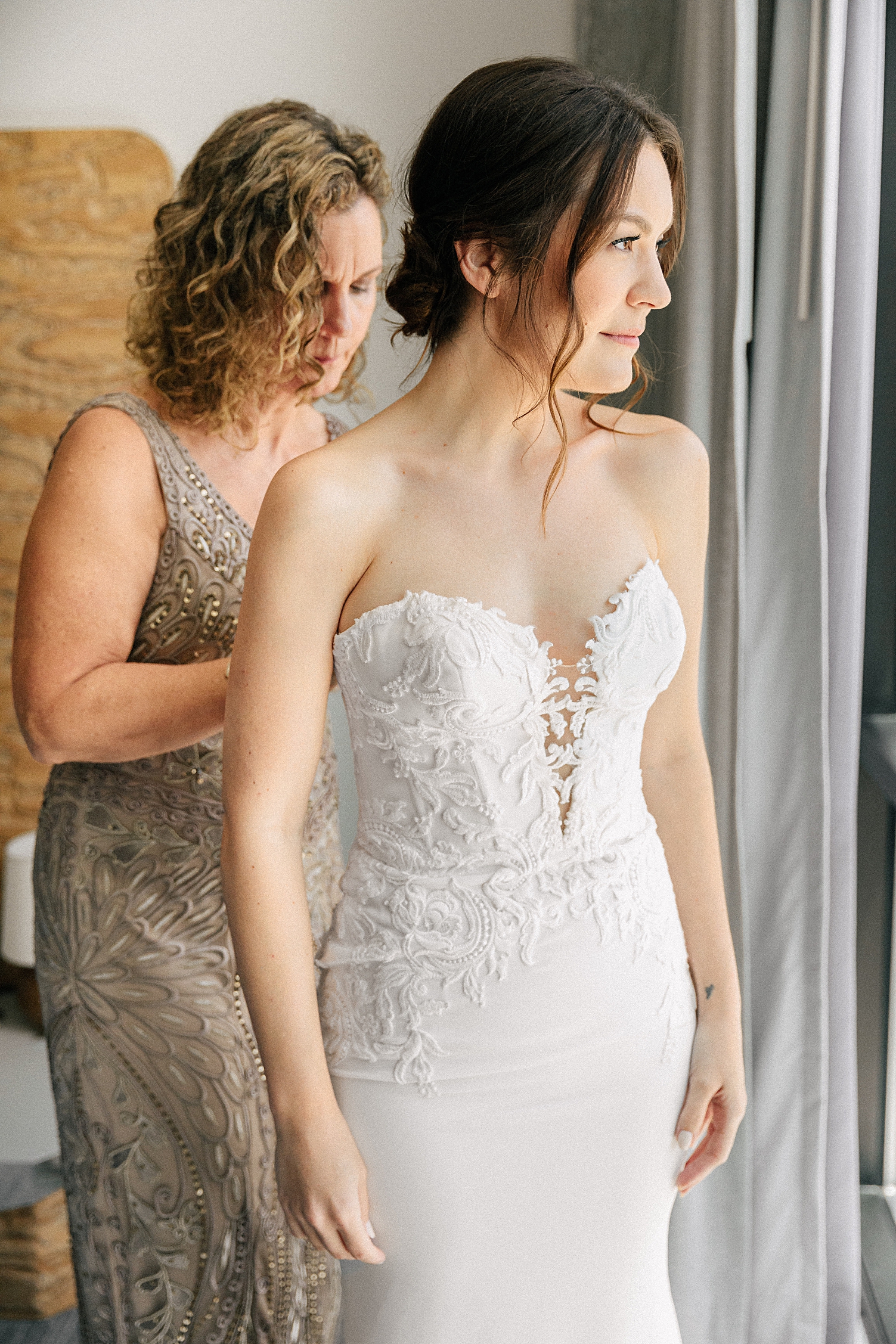 mother helping bride into wedding dress