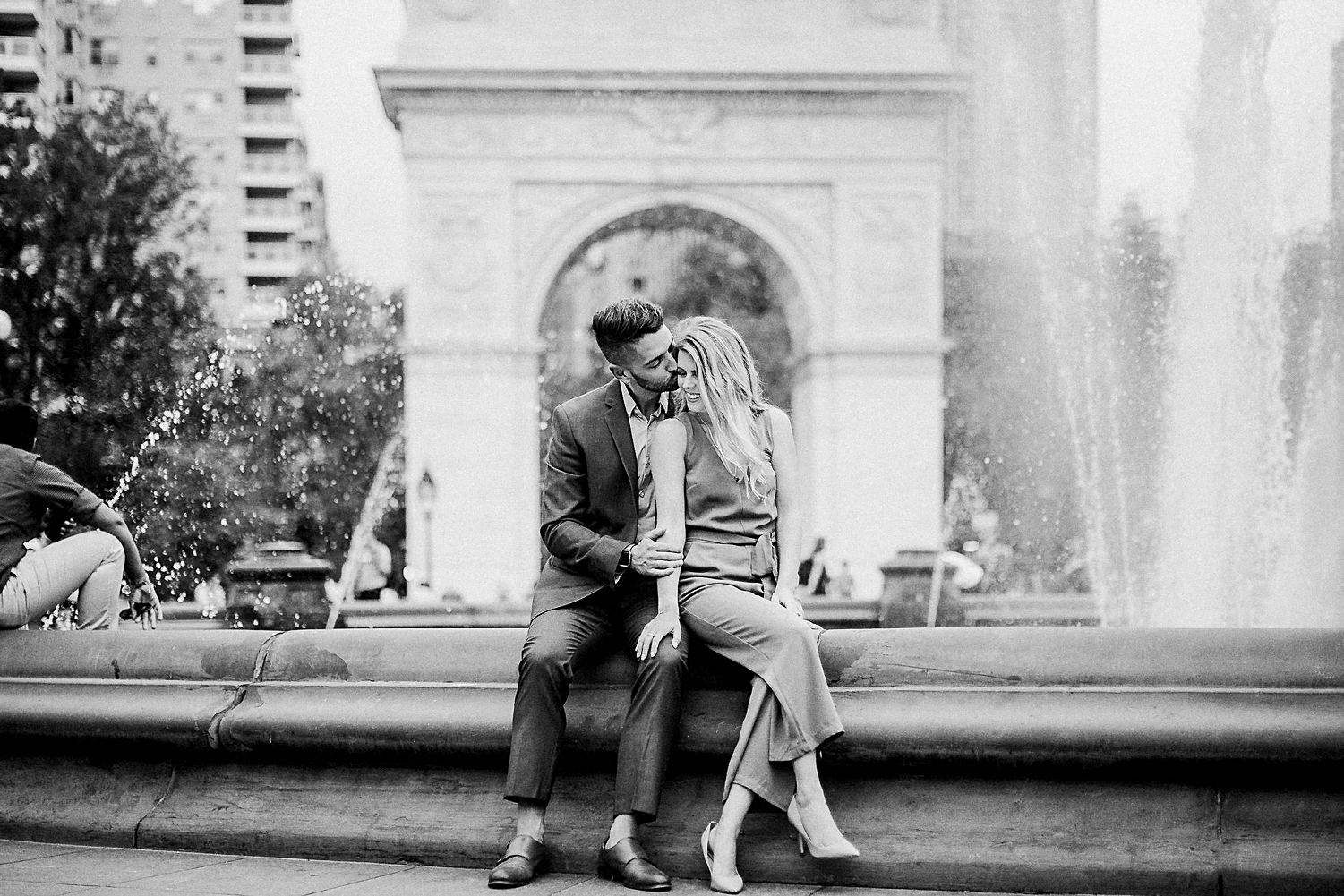 Man and woman sitting together on fountain Washington Square Park New York City