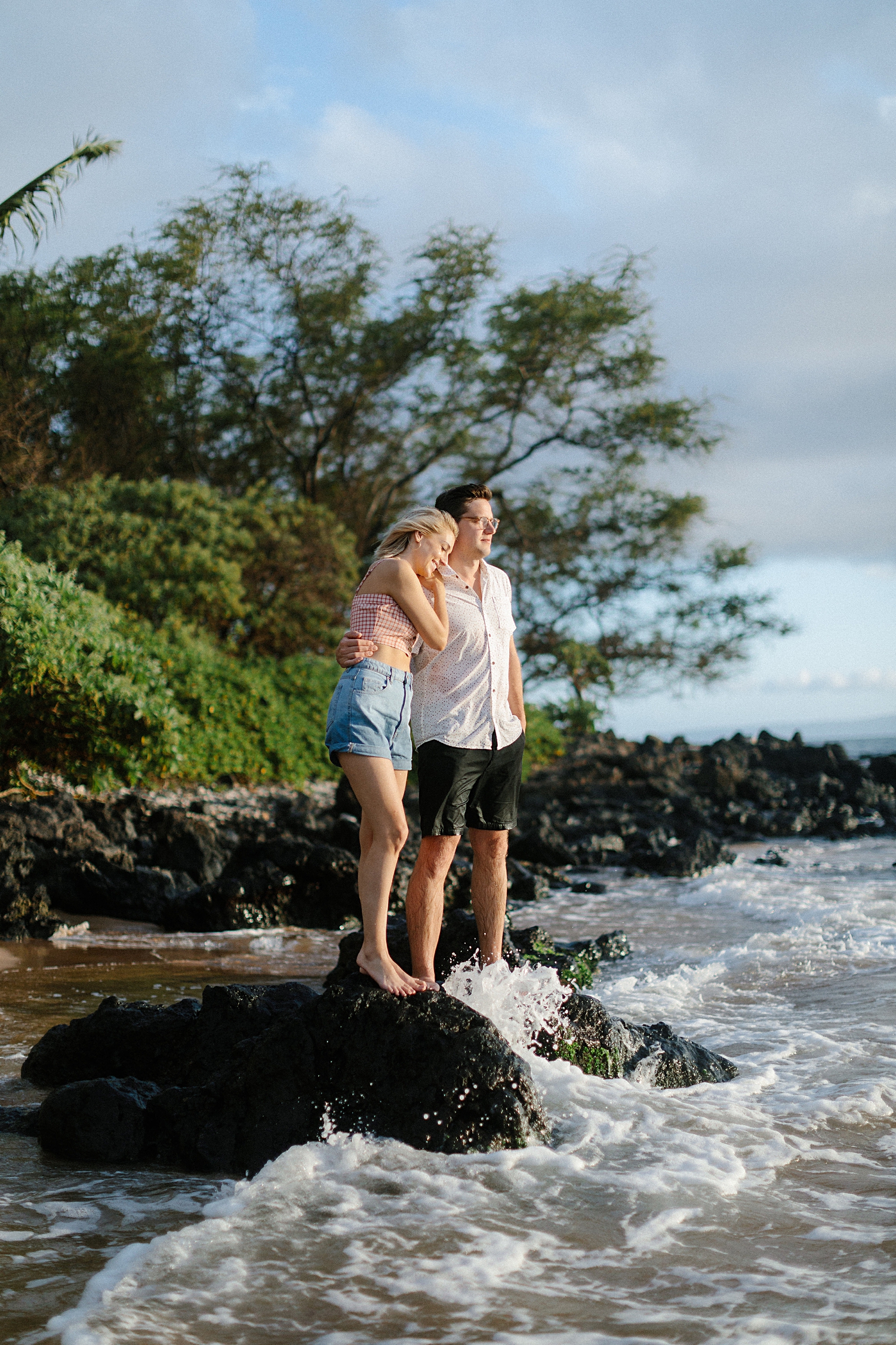 girl hugging man standing on black rock Kihei beach hawaii