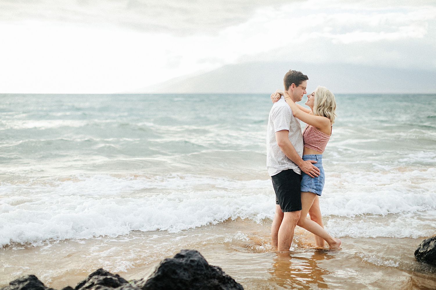 couple on Maui beach standing in water hugging