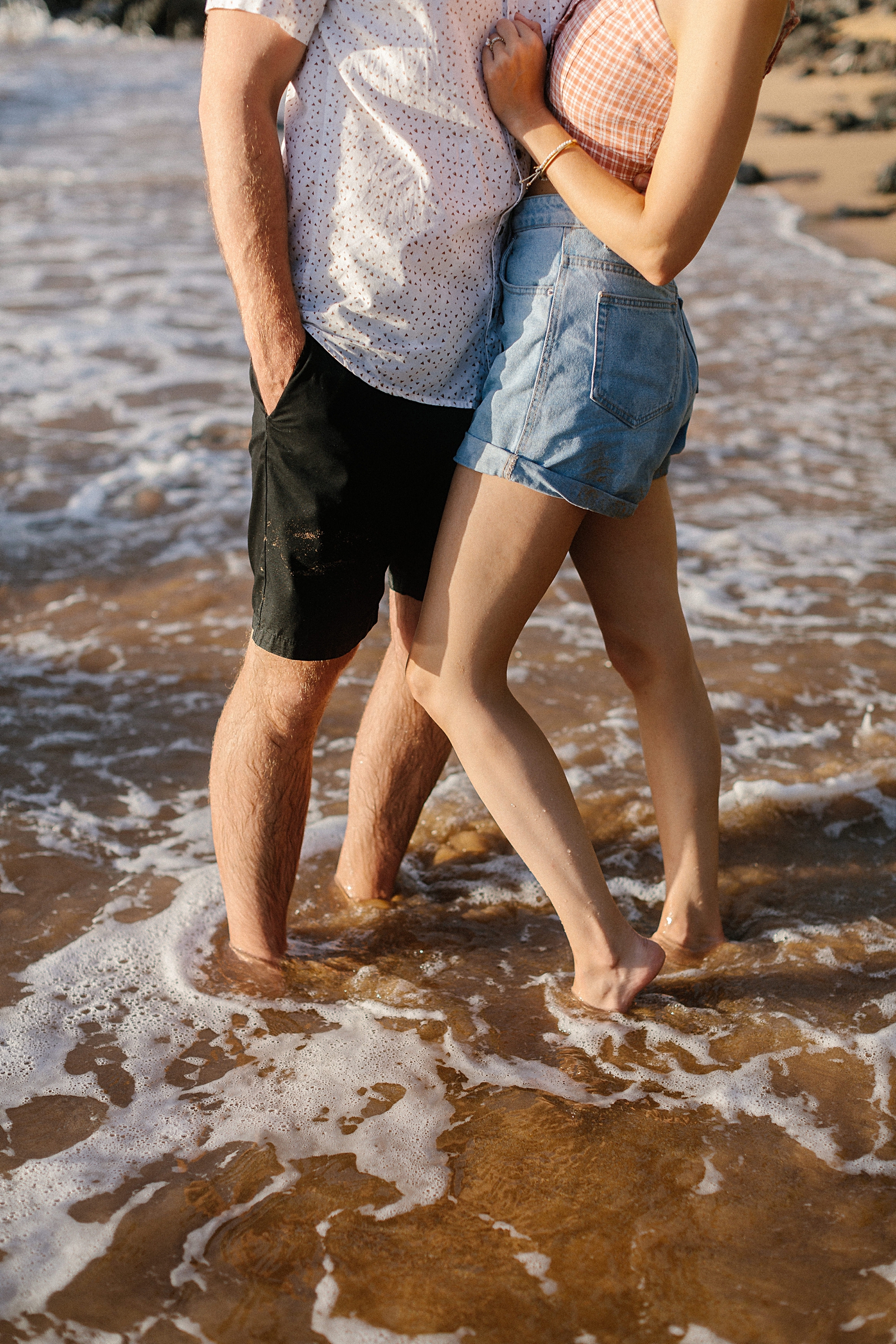 couples legs standing on beach 