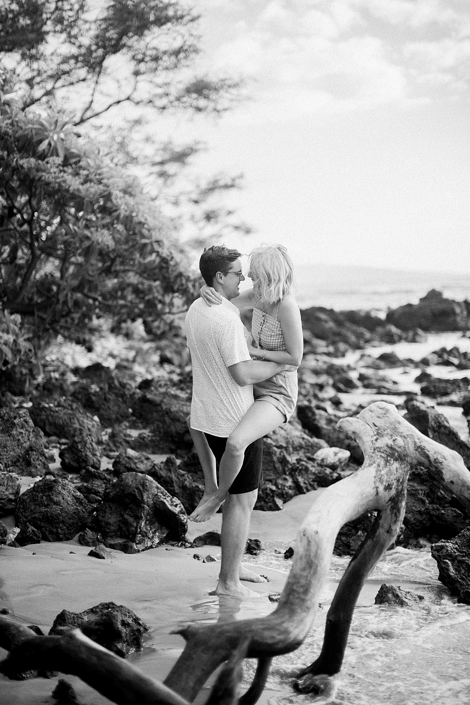 man holding girl in arms on beach black and white