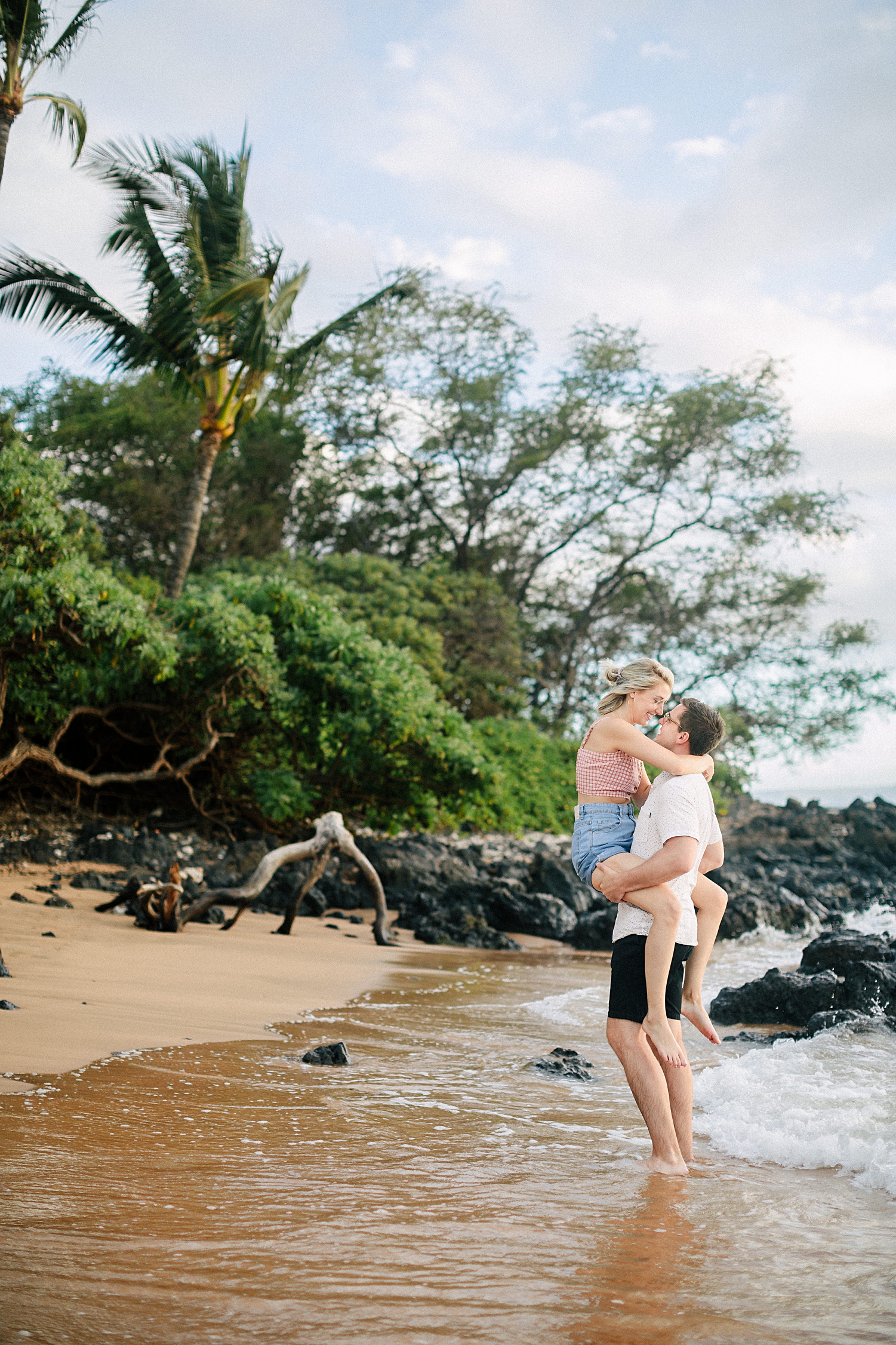 man holding girl in arms on wailea beach in hawaii
