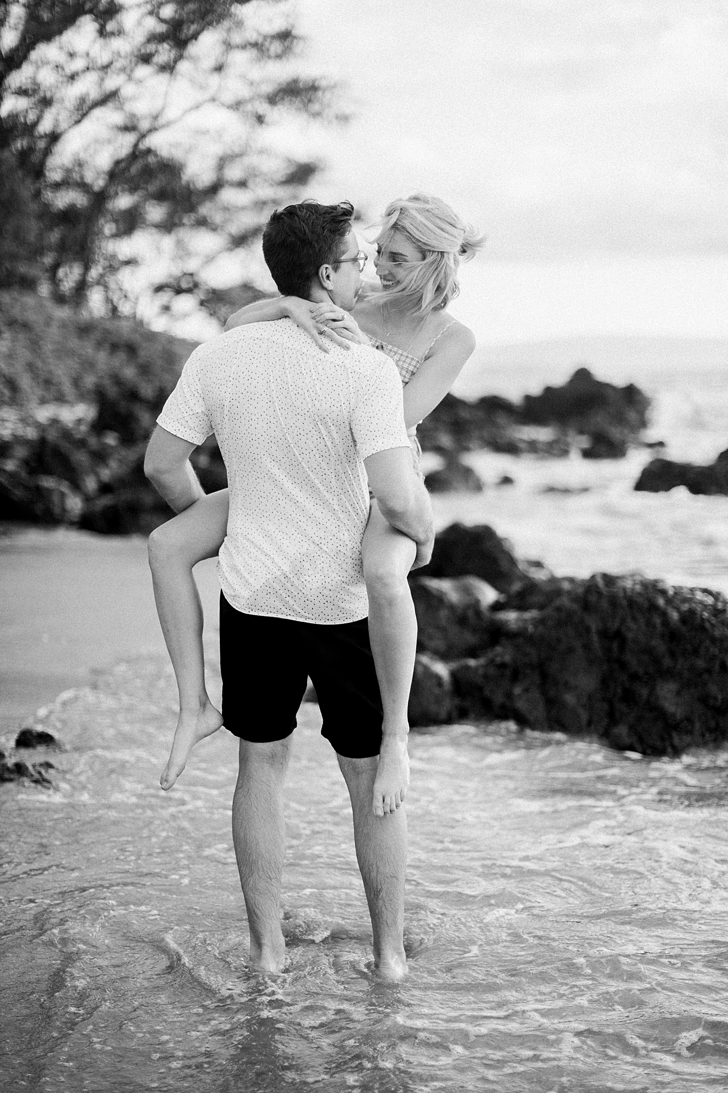 man holding girl in arms on wailea beach in hawaii black and white