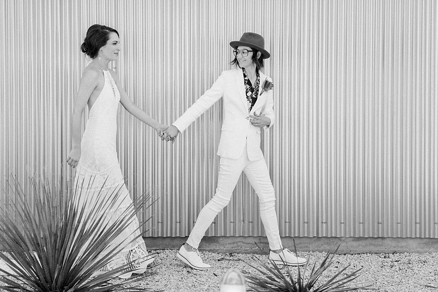 bride holding hands and walking by metal wall