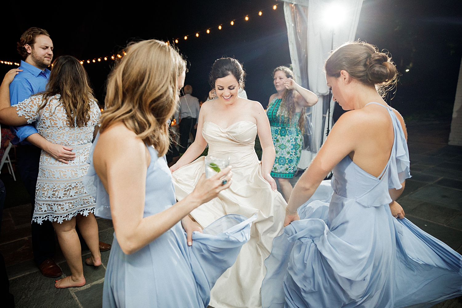 bride dancing with bridesmaids in blue dresses at wedding reception