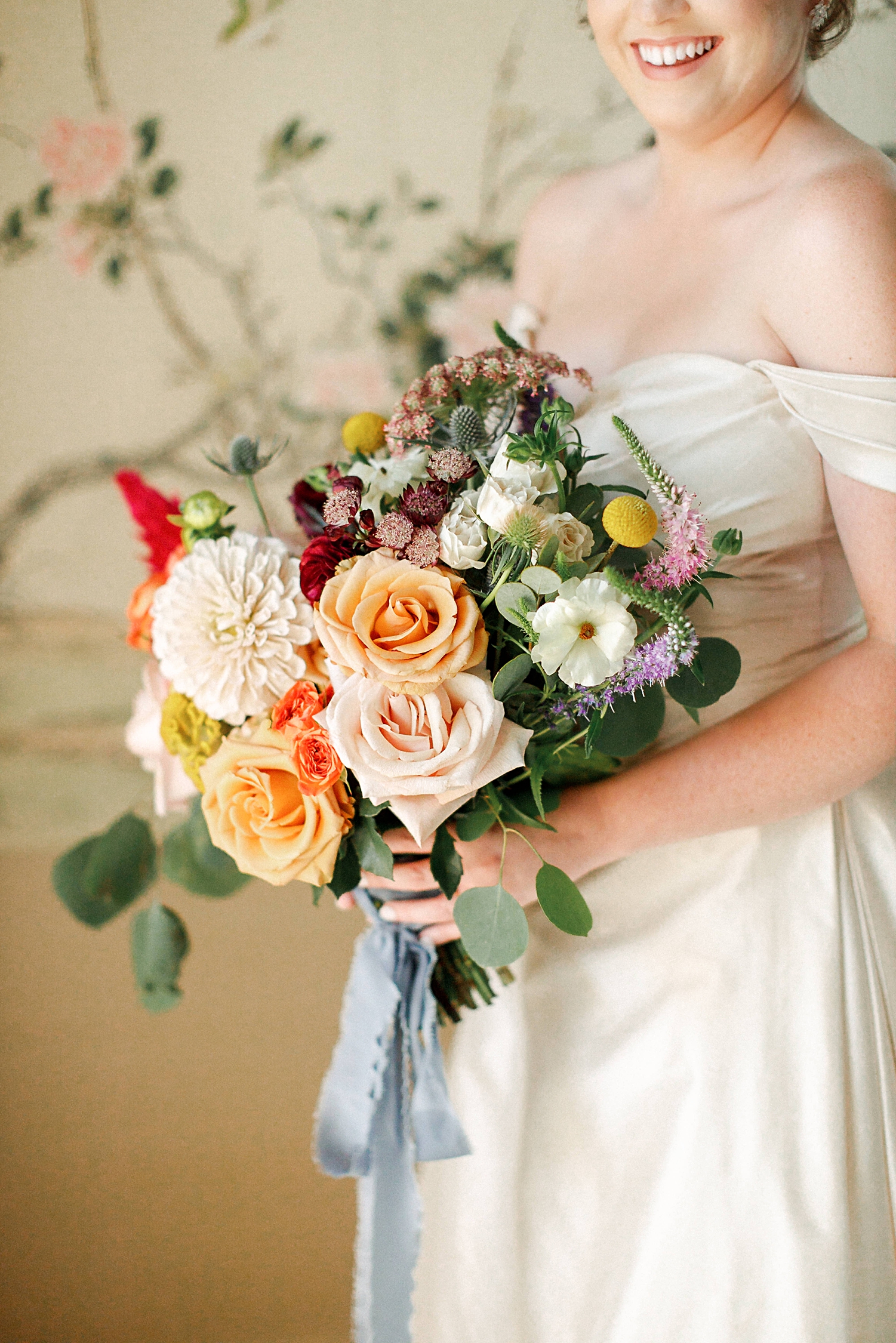 colorful wedding bouquet with blue ribbon held by bride