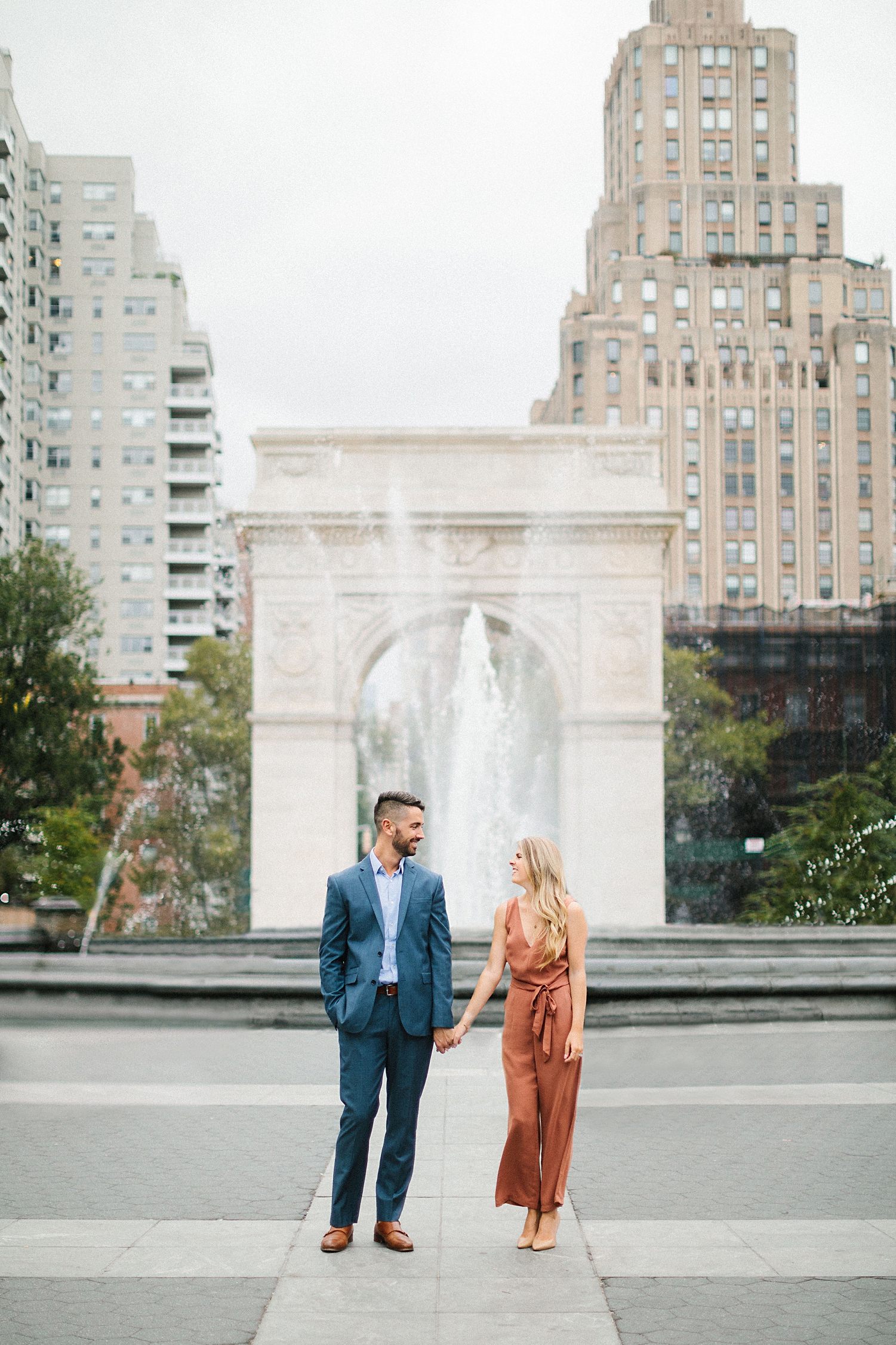 couple standing in front of Washington square park fountain and arch in greenwich village engagement