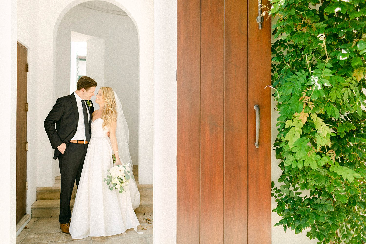 Bride and groom in white doorway Alys Beach Florida embracing