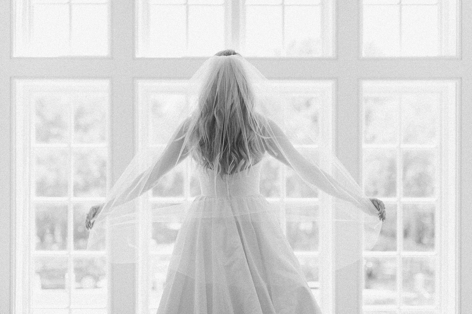 Bride in wedding dress and veil getting ready at Seaside Chapel window in Florida
