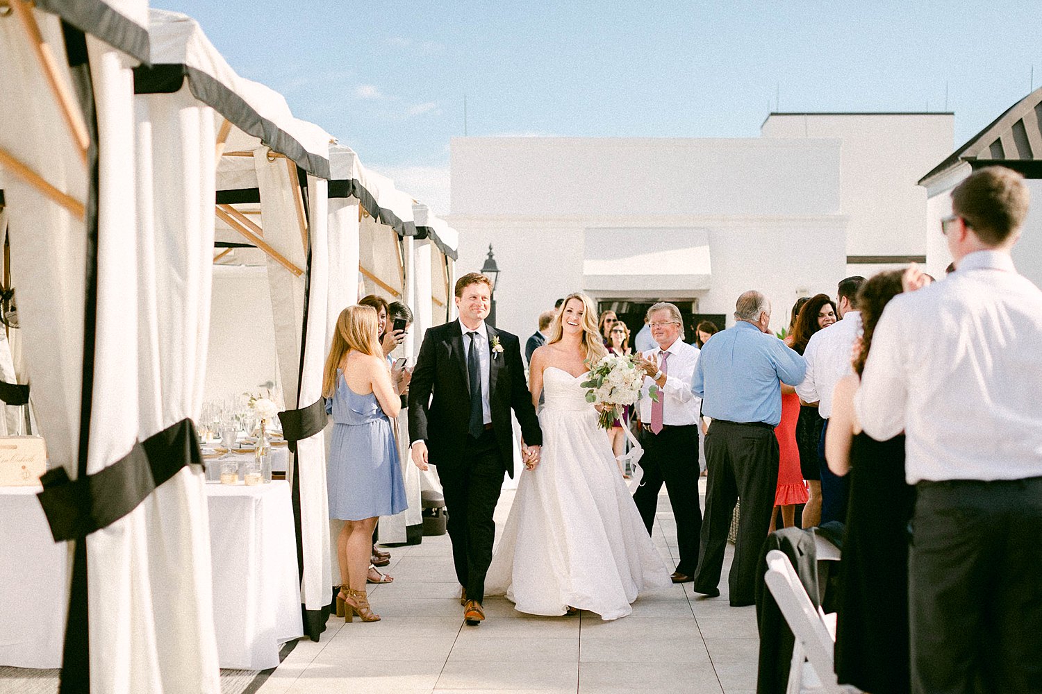 Bride and groom walking into outdoor patio wedding reception at the Pearl Hotel 