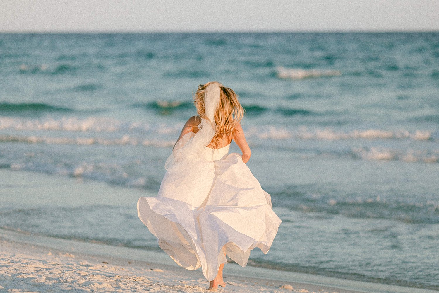 bride running barefoot on beach day at the Pearl Hotel in Rosemary Beach Florida