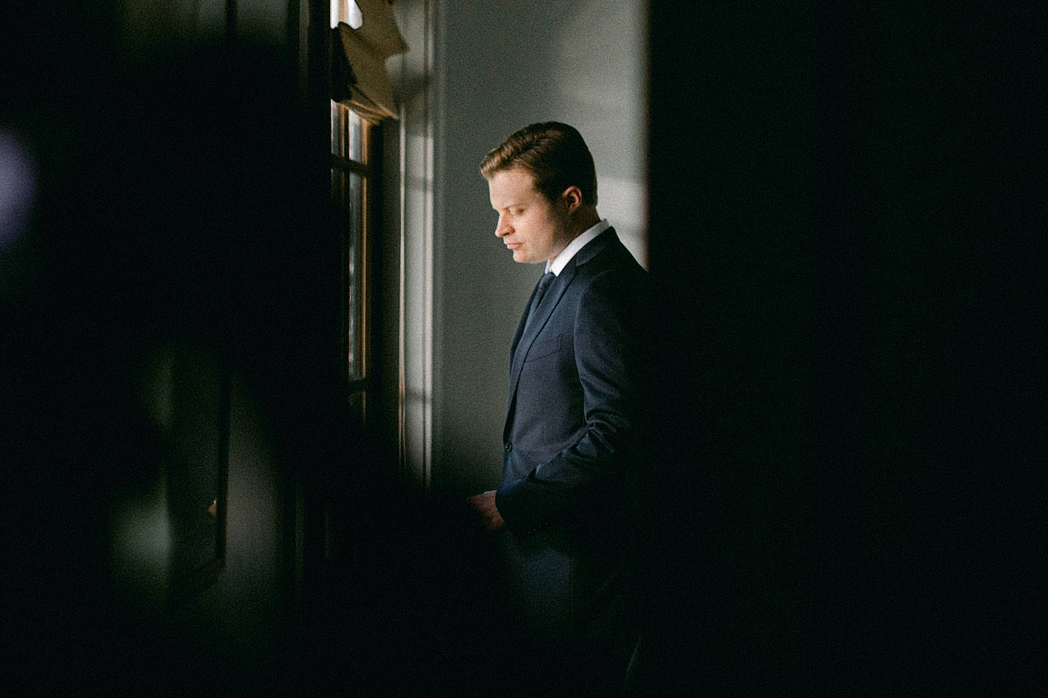 man in suit looking out window