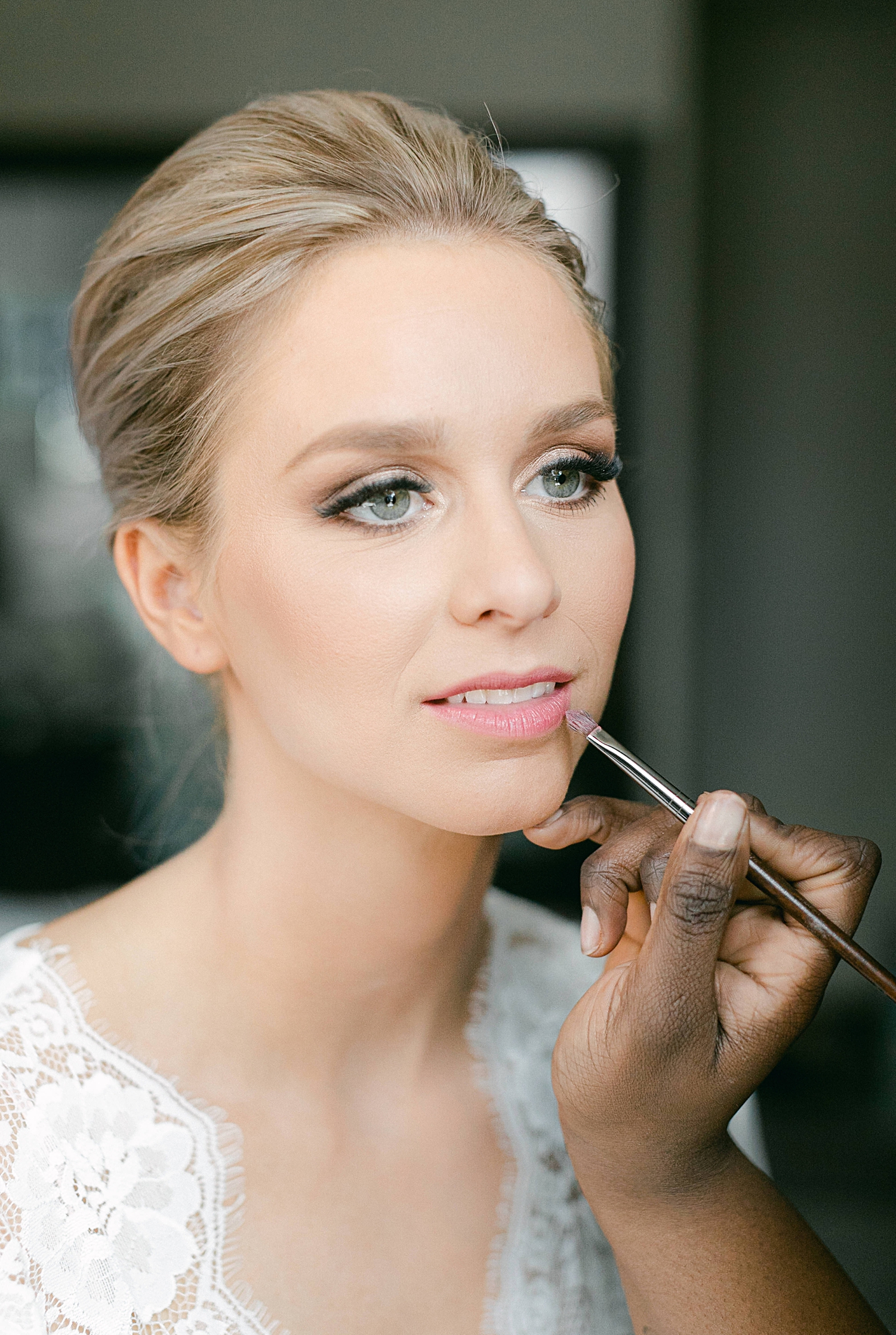 Bride getting lip makeup done on wedding day