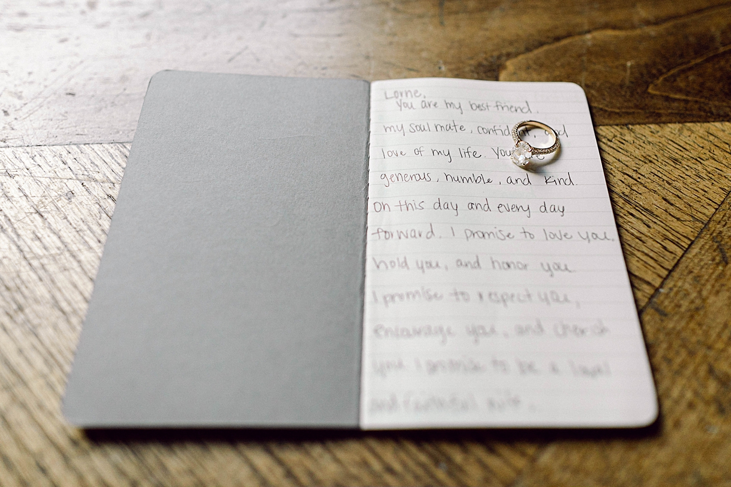 engagement ring sitting on hand written Wedding vows written in small book 