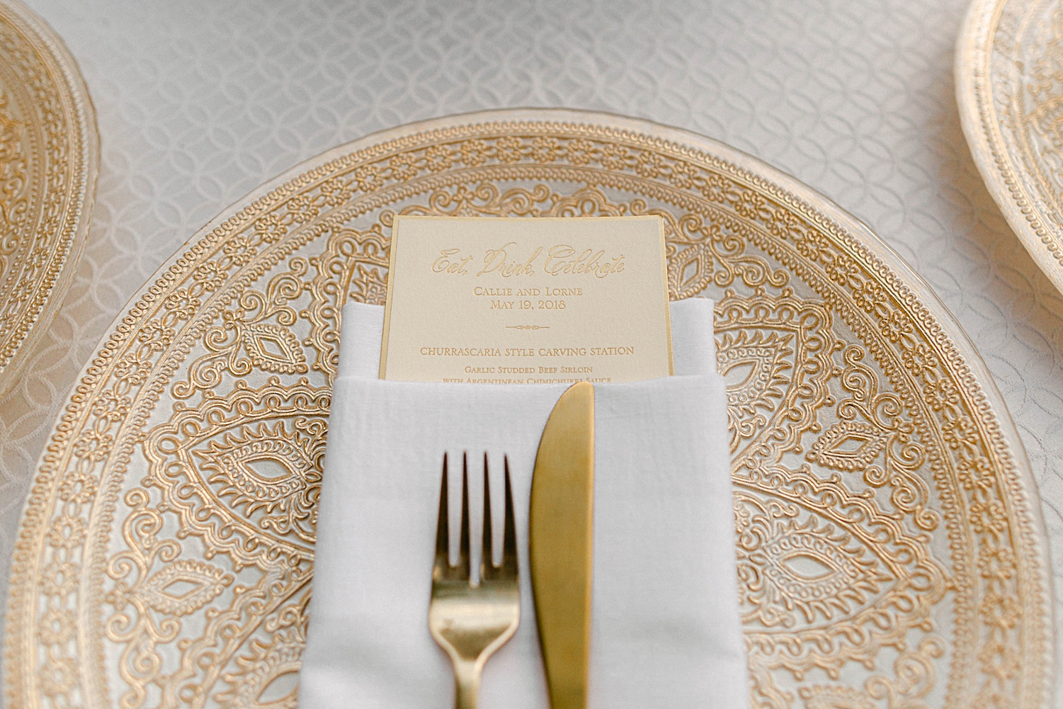 Golden fork and knife on charger with name tag wedding reception