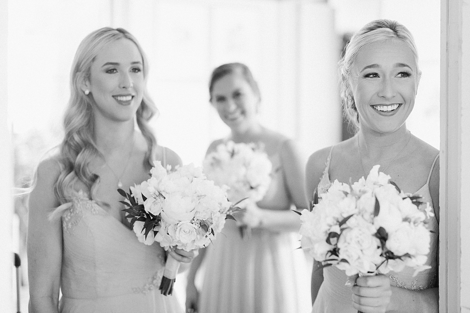 Bridesmaids holding bouquets smiling black and white