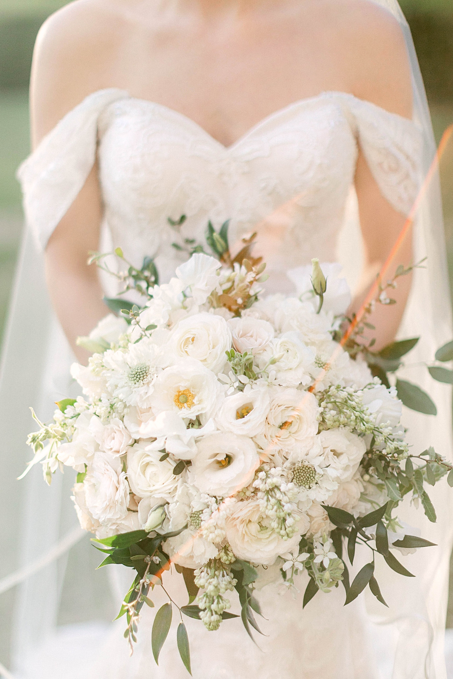 bride in lace wedding dress holding white and green floral bouquet