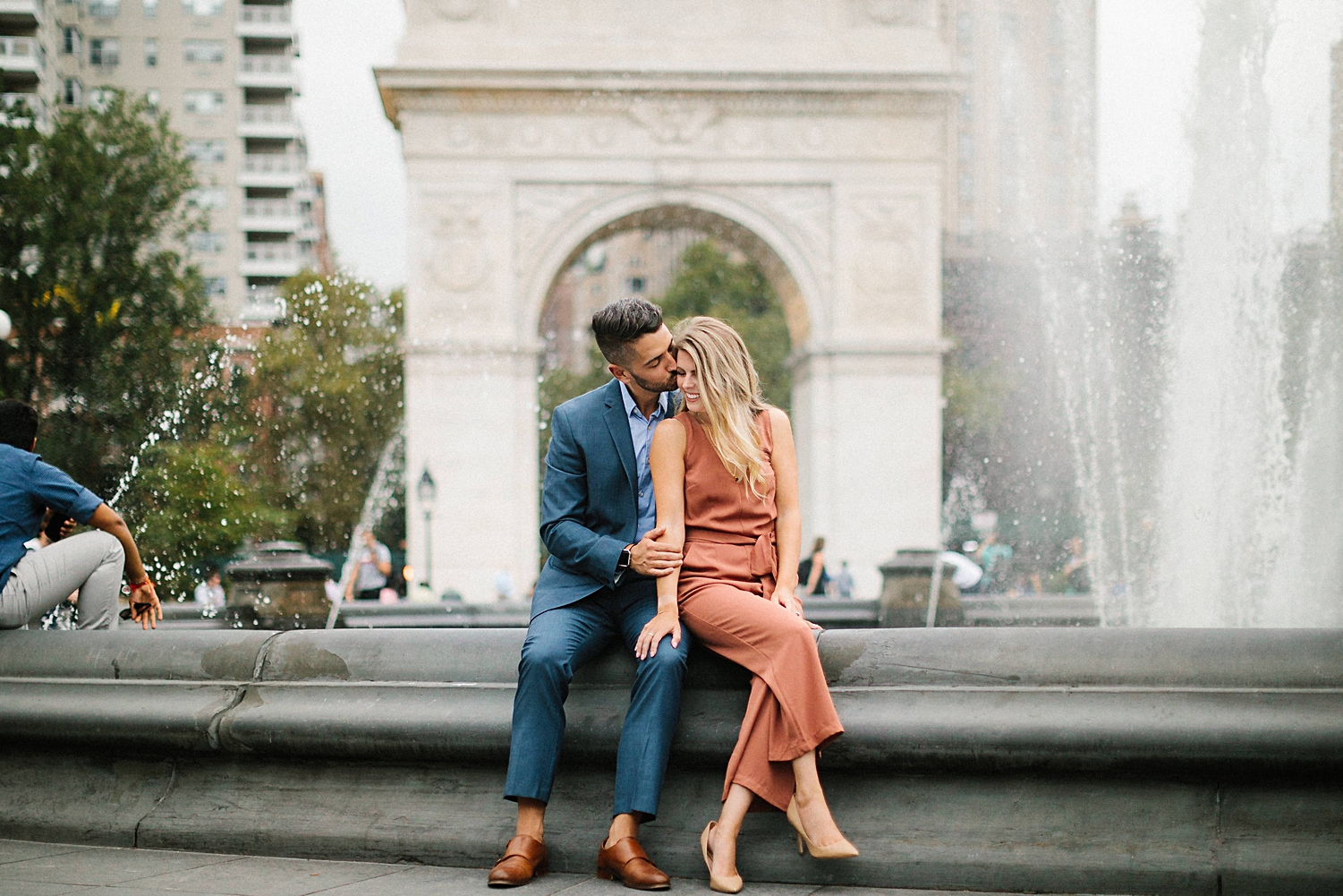 couple sitting by Washington square park fountain greenwich village engagement