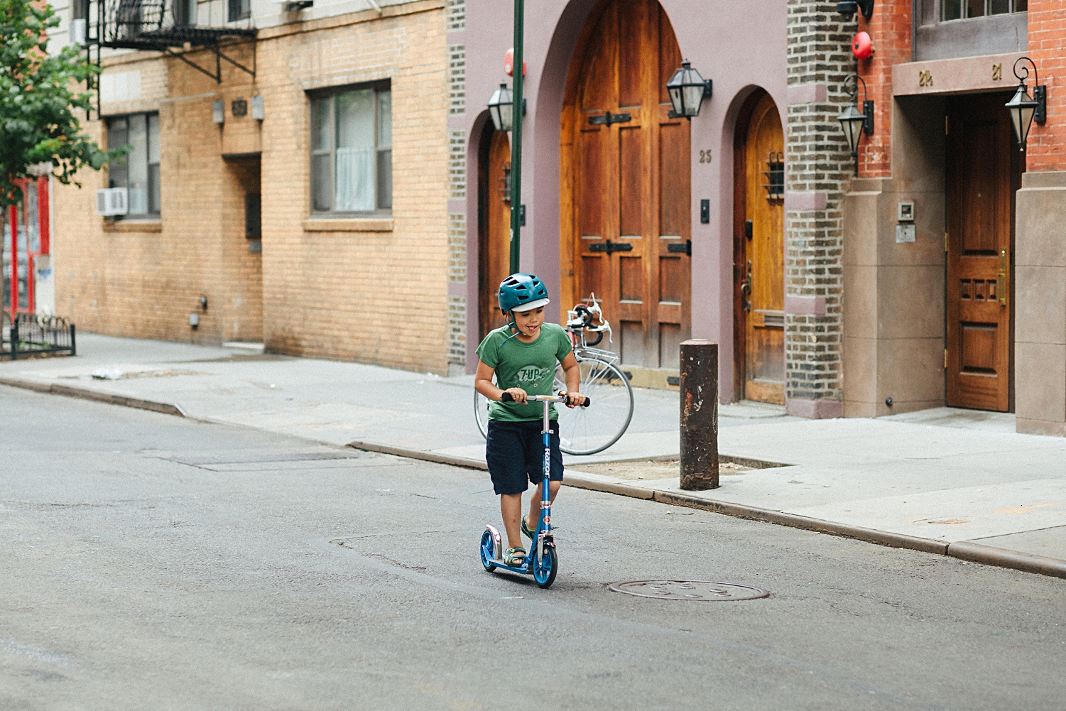 boy in green shirt riding scooter down cornelia street in new york city