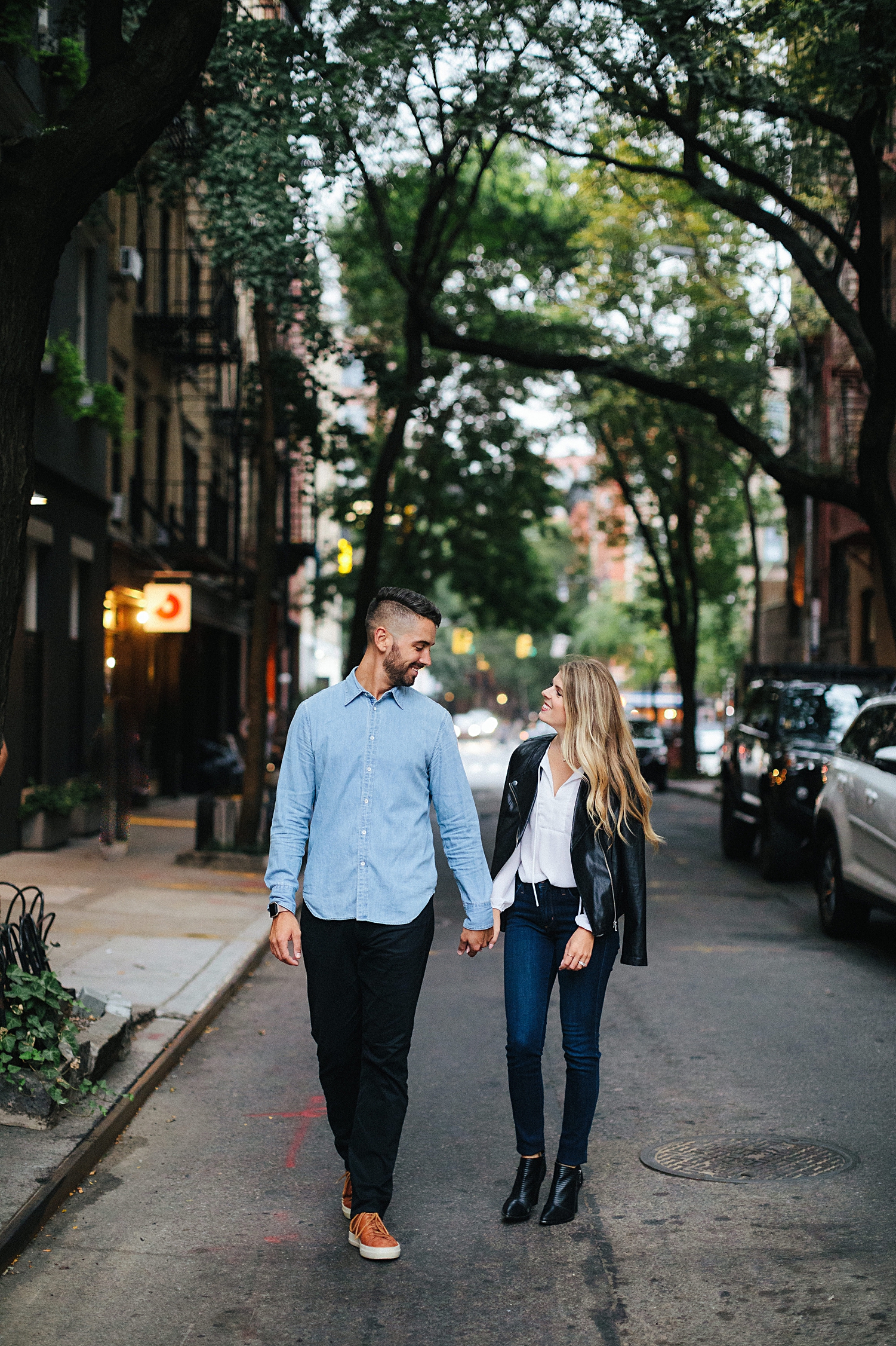 couple holding hands walking down street in Greenwich village engagement