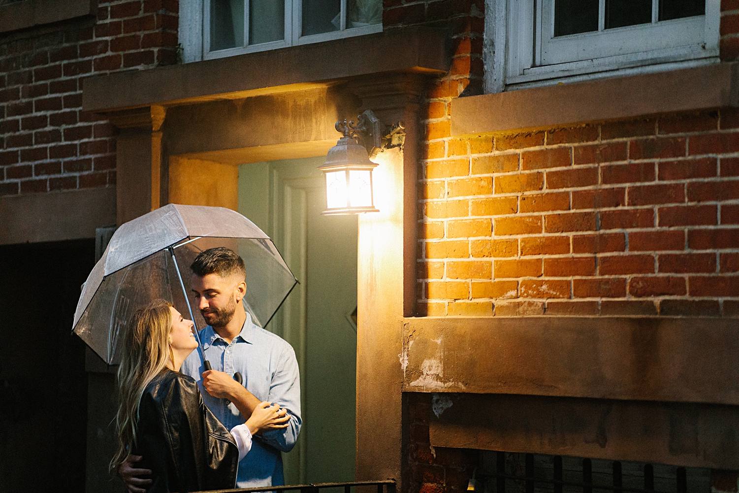 couple embracing and holding umbrella under street light Greenwich Village Engagement