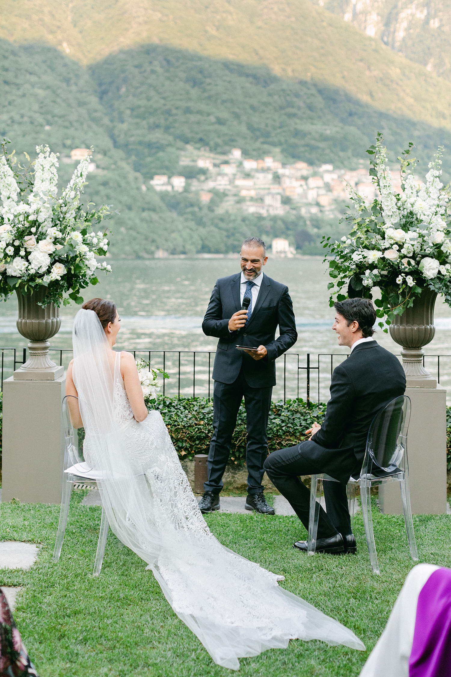 bride and groom sitting at ceremony altar in front of Lake Como wedding destination