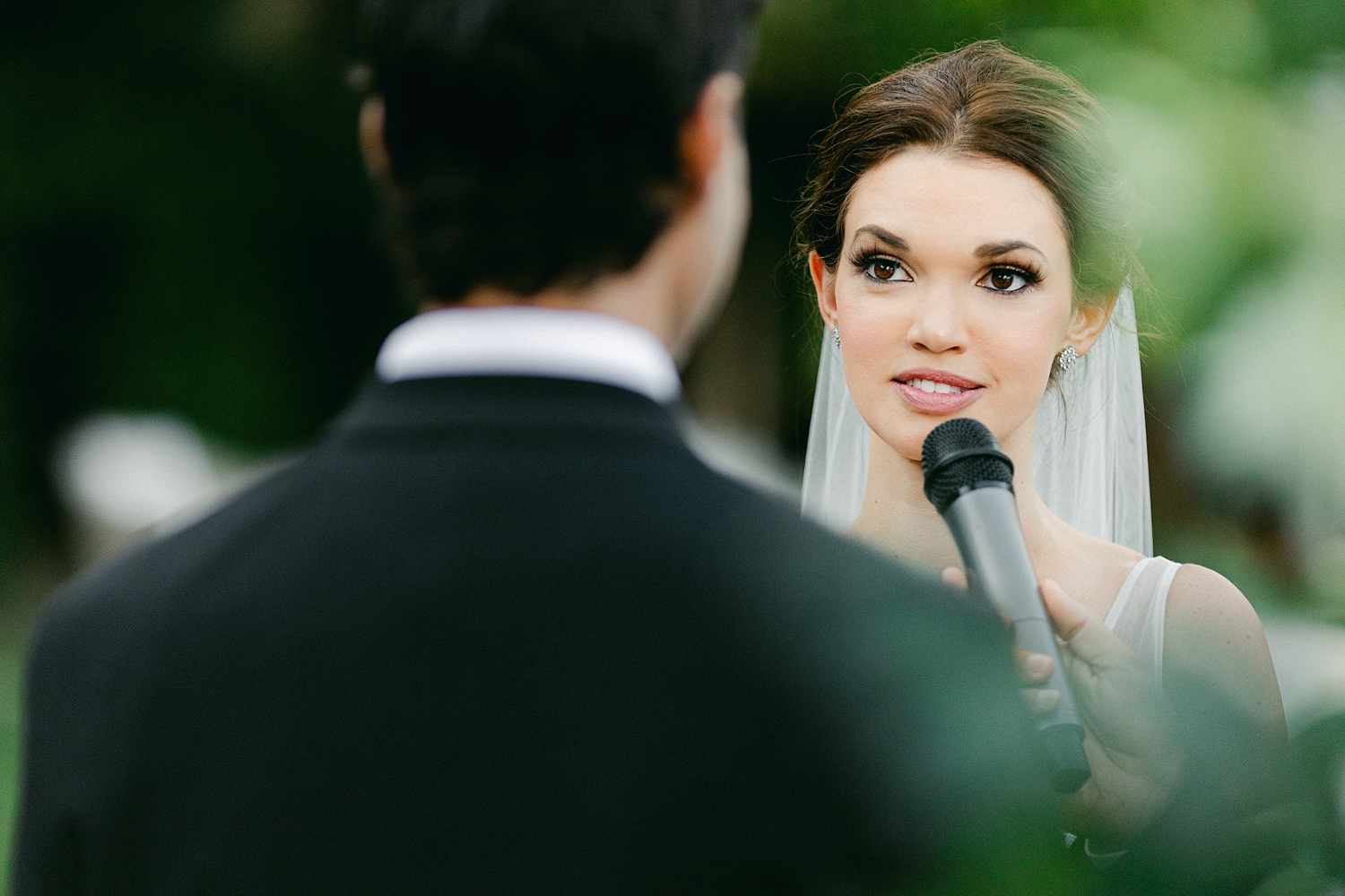 Bride exchanging vows in microphone to groom during wedding ceremony