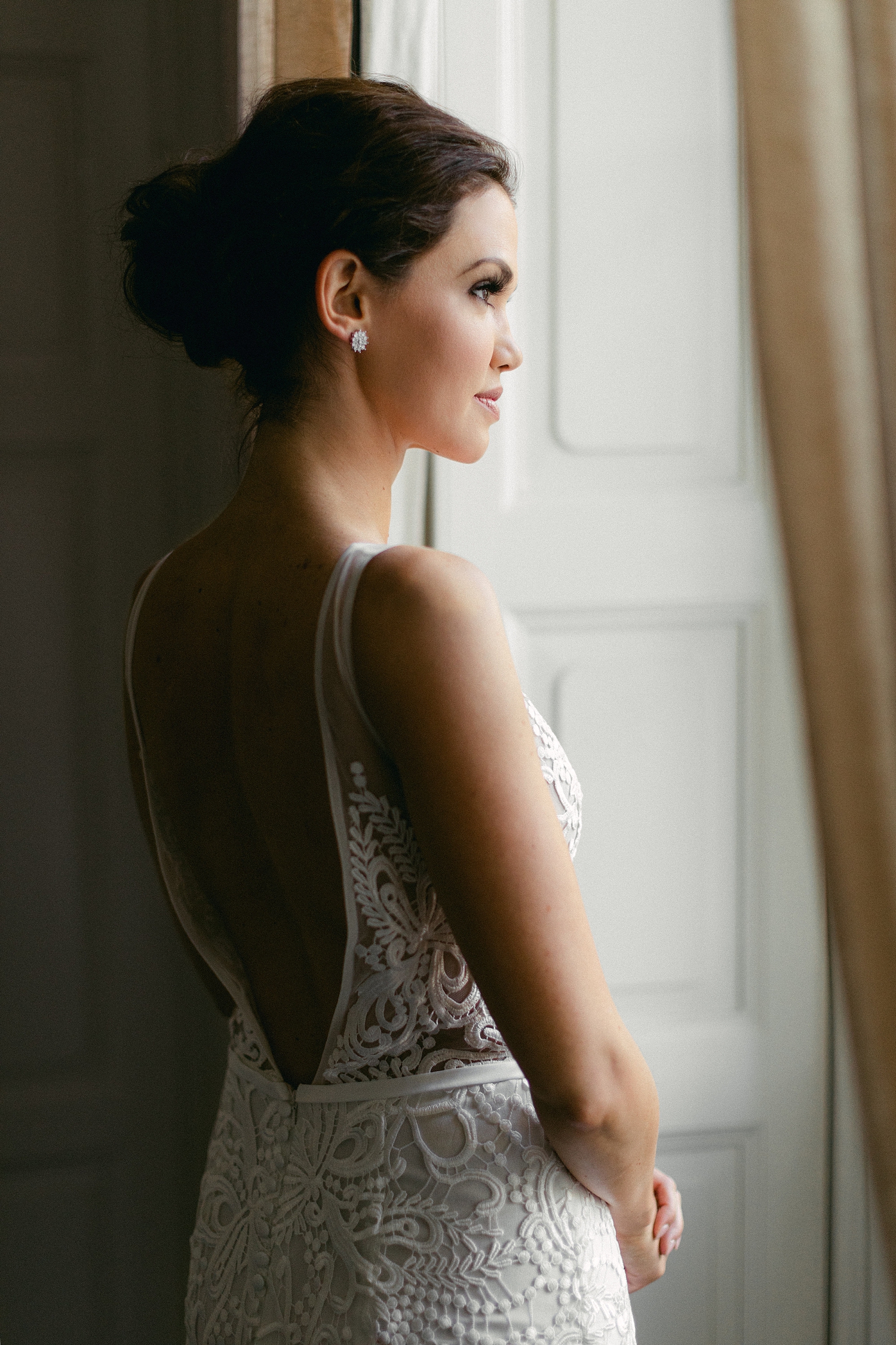 bride in white lace wedding dress looking out window before wedding ceremony in Lake Como Italy