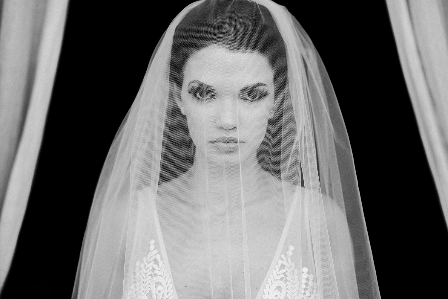 Bride under veil in white lace wedding dress against black background at Lake Como Wedding