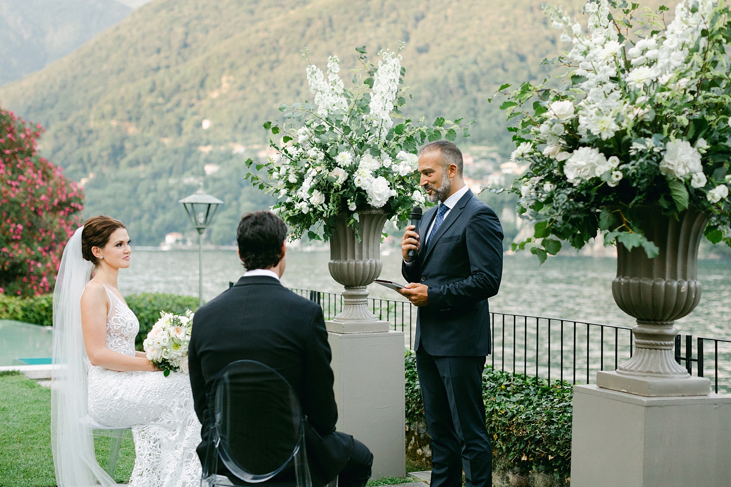 groom in tuxedo sitting at Italian wedding ceremony in front of mountains
