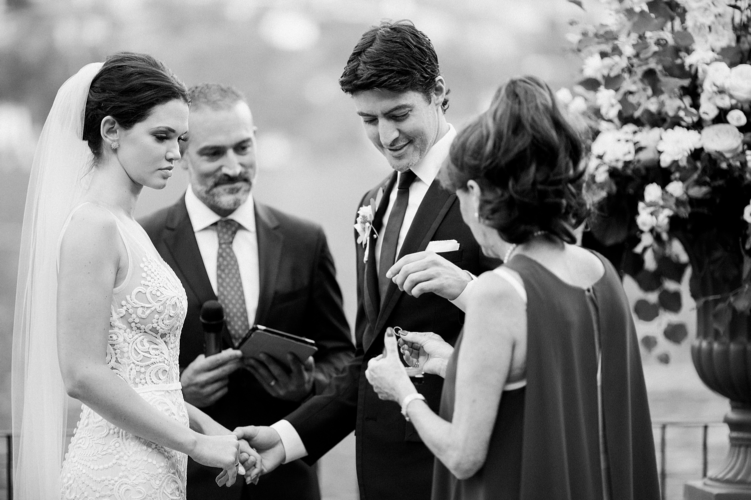 bride in white lace dress holding hands with groom at outdoor Lake Como wedding ceremony black and white