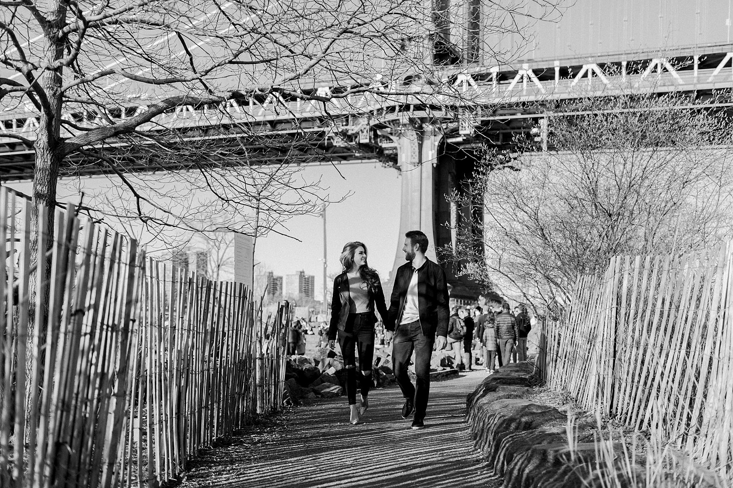 Couple holding hands walking by bridge manhattan at sunset brooklyn engagement session