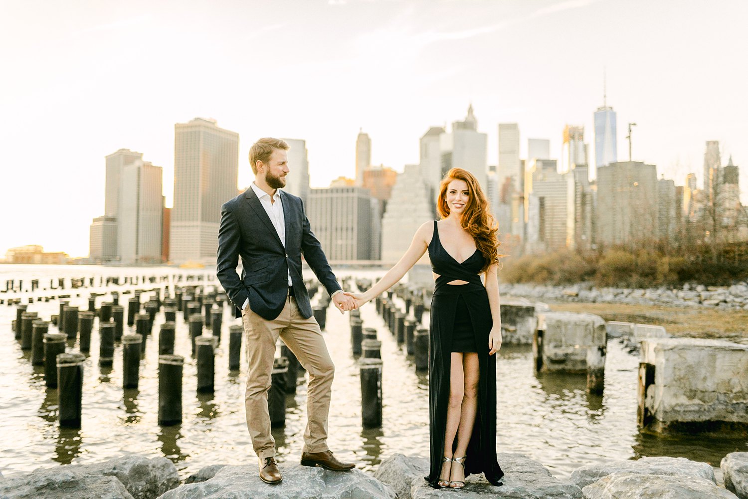 Downtown Manhattan Skyline from Brooklyn pier couple holding hands engagement session at sunset
