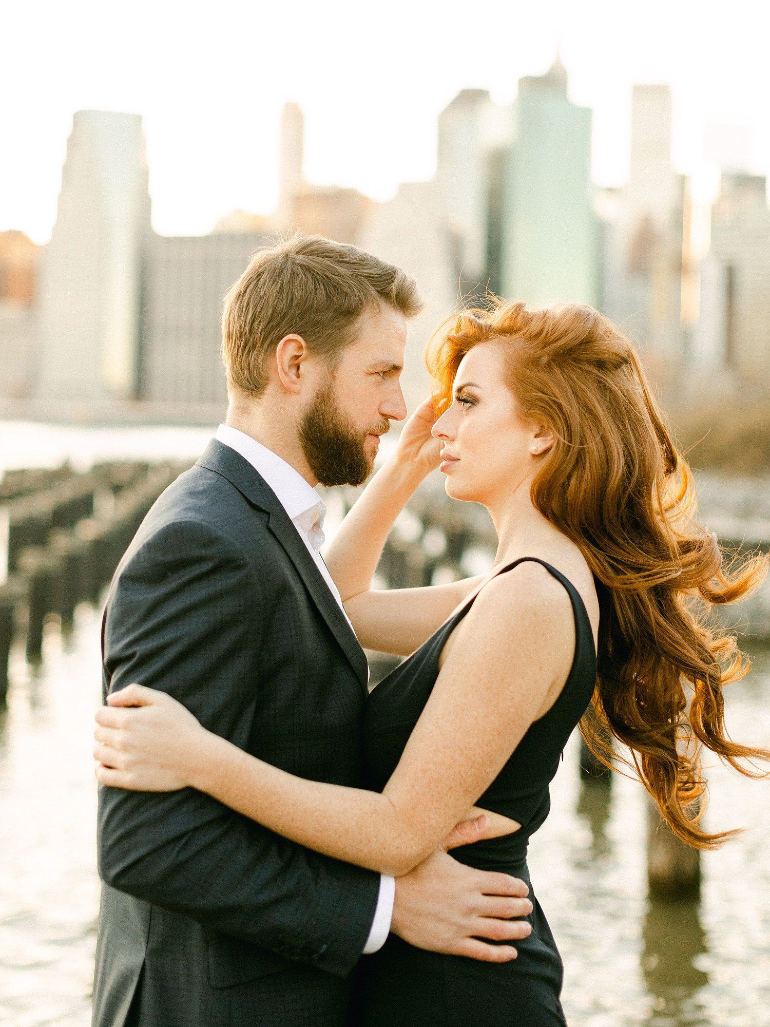 Downtown Manhattan Skyline from Brooklyn pier couple hugging engagement session at sunset