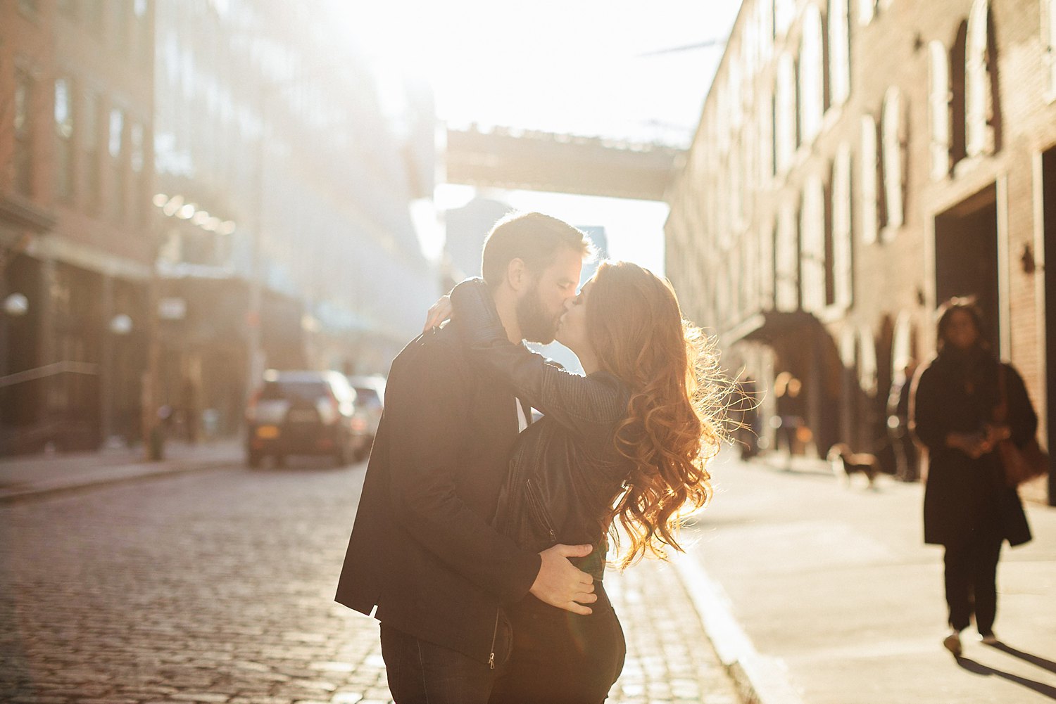 Couple embracing and kissing on NYC street at sunset during Brooklyn engagement