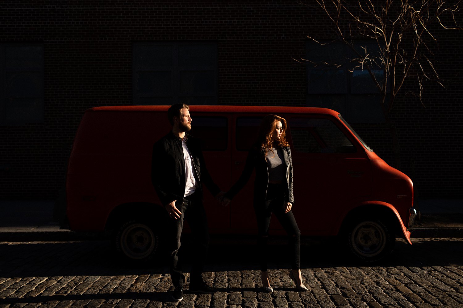 couple standing on street silhouetted in front of red van