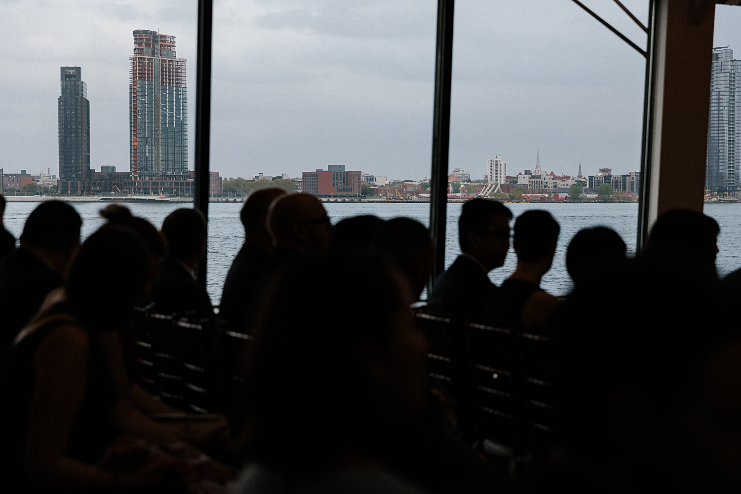 silhouettes of wedding guests sitting against east river new york city