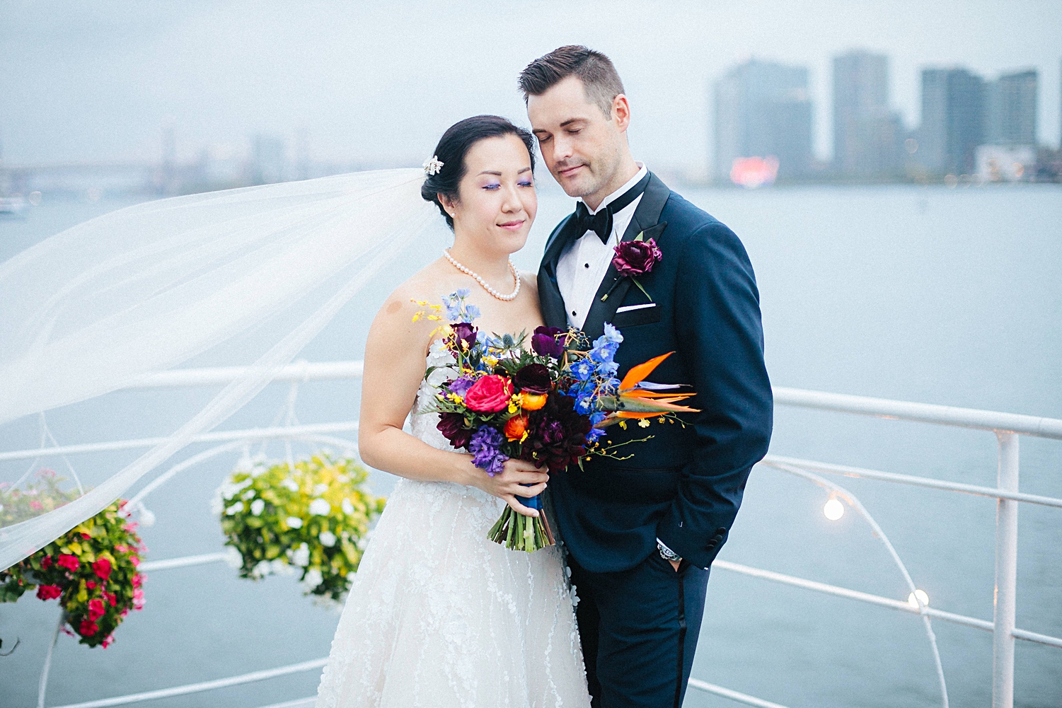 bride and groom standing together at water club in front of east river new york city