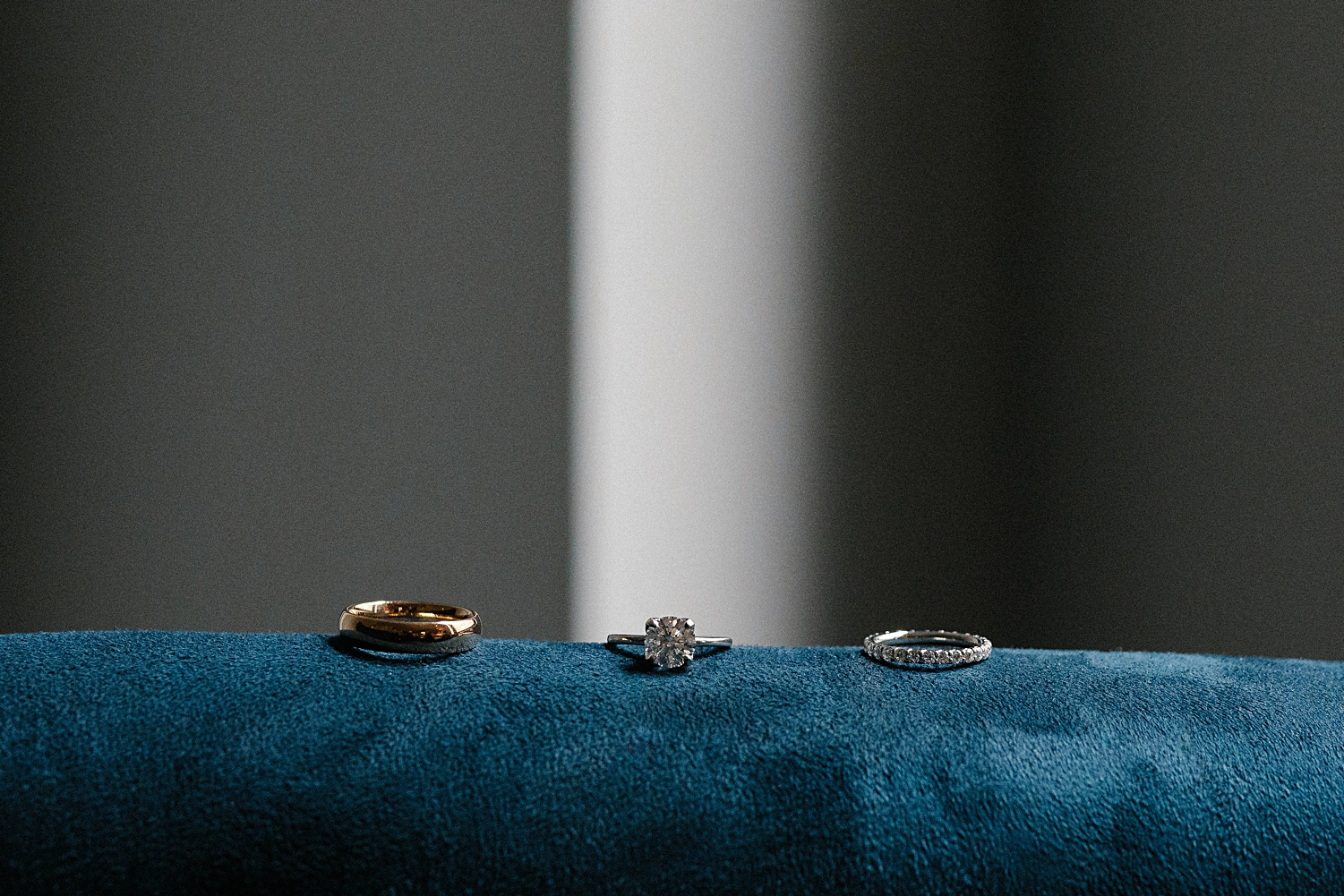 bride and groom diamond rings sitting on blue surface